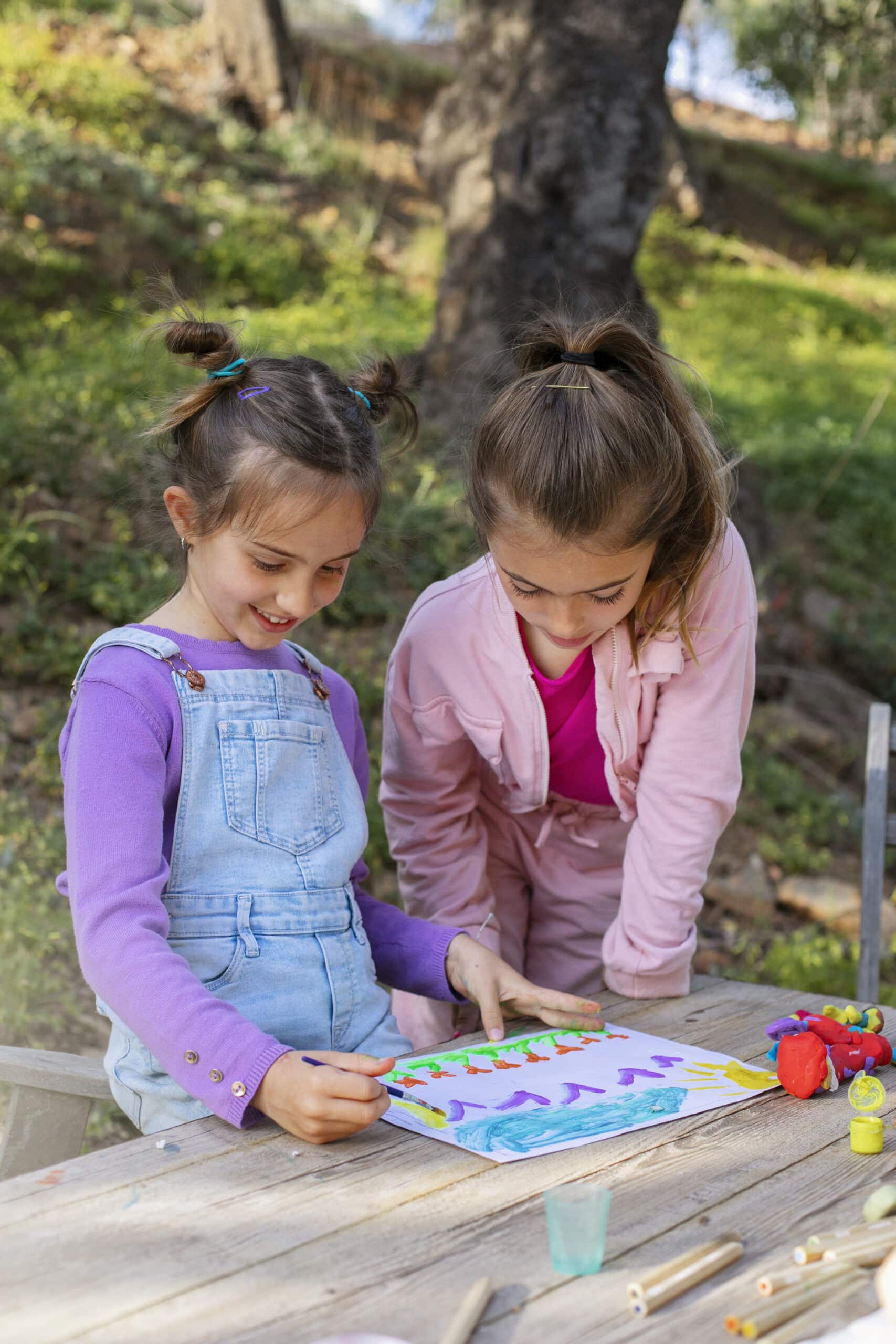 Two young girls playing together outside with an enriching ABA activity